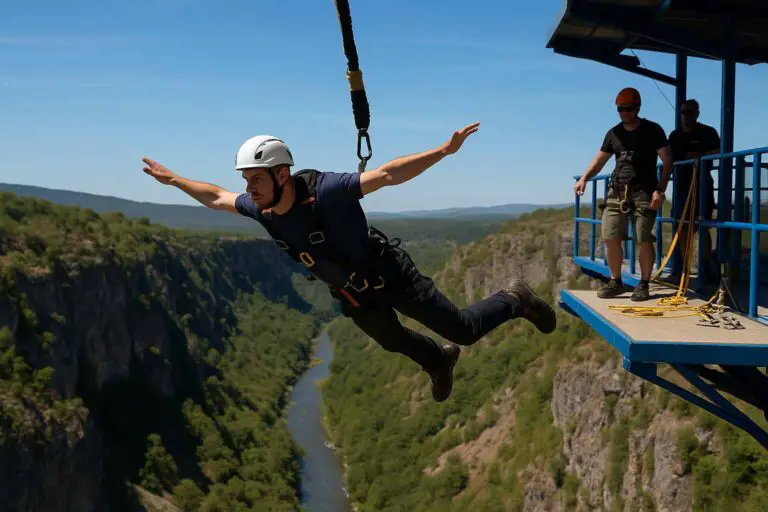 Bungee jumper mid-fall above a canyon with visible safety harness and launch crew on platform.