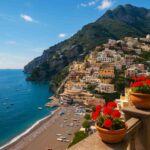A scenic coastal village on the Amalfi Coast with colorful cliffside houses overlooking the blue Mediterranean Sea, sunny skies above, and boats docked below.